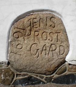 Rostgaard-stenen fra 1691, som i dag er indmuret i den ene af Damgaardens gavle ud mod Mørdrupvej.