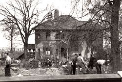 Fotografiet er fra maj 1945 og viser internerede, der under frihedskæmpernes overvågning, rydder op efter Gestapo. Huset var kamoflagebemalet