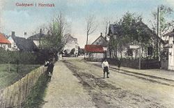 Hornbæk Hovedgade, 1897, hvor købmandsgården netop er opført og man ser det første udsalg med rødt tag fra 1889, hvor senere Gemüse Carls forretning kommer.