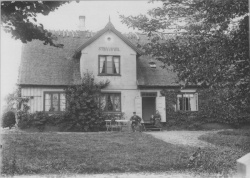 Stranddals hovedbygning med familien Bastiansen ved havedøren, ca 1905